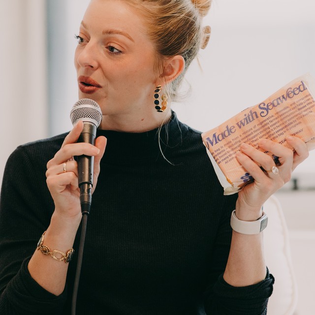 A Marketplace of the Future speaker on seaweed packaging, holding a Made with Seaweed pack on stage at MOTF NYC 2026